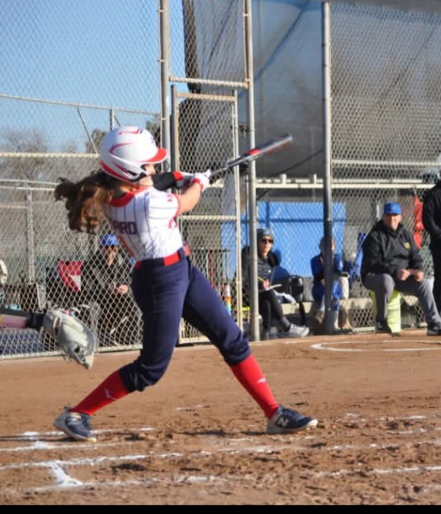 Female softball player swinging bat during game